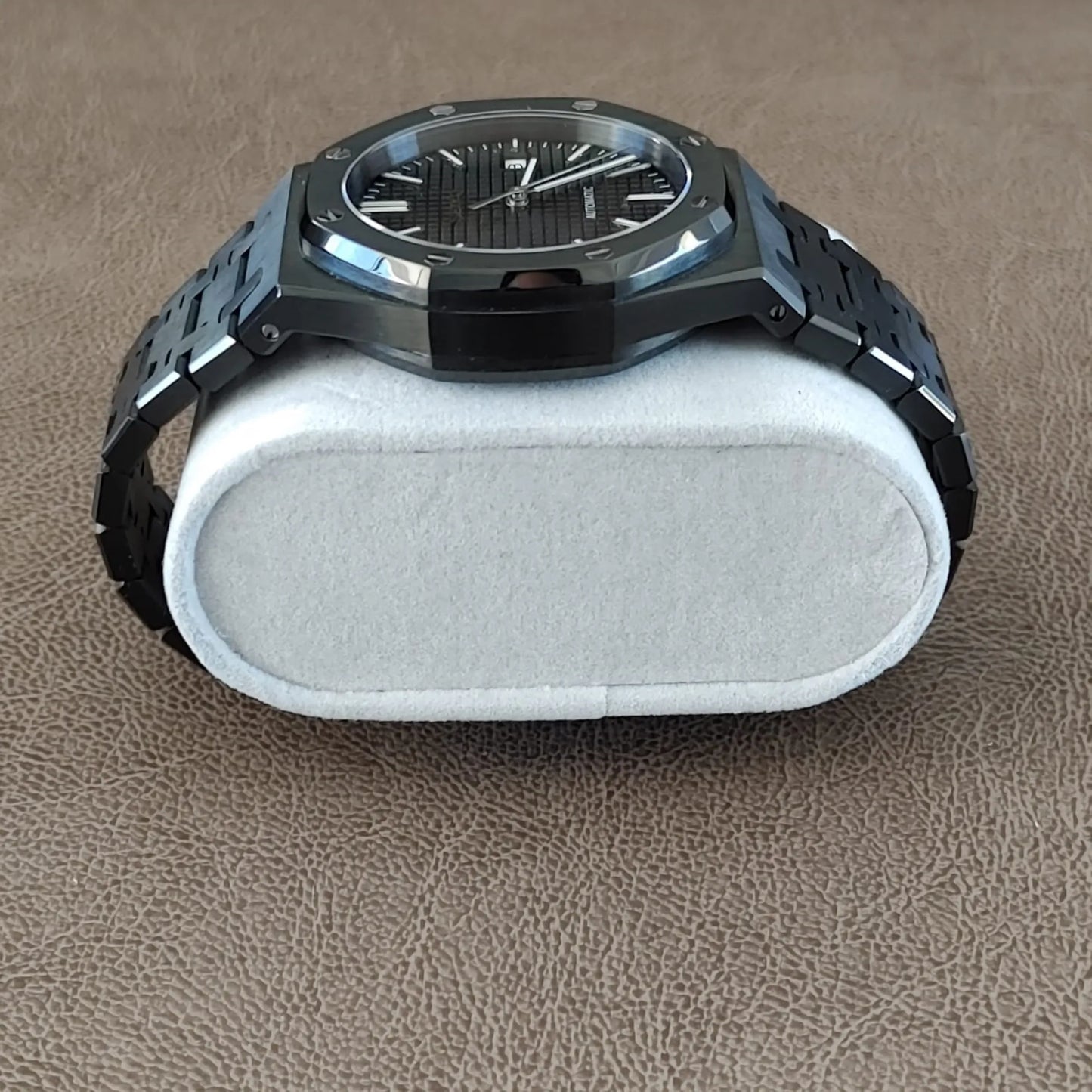 Seiko NH35 black and silver 41mm watch with a textured dial and metal bracelet resting on a white cushion.