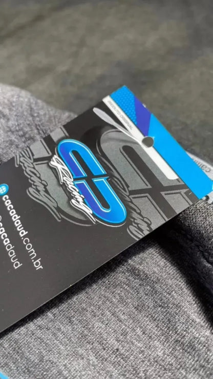 Cobalt blue and black graphic tag on gray soft fabric, featuring stylized "CD" logo and text.