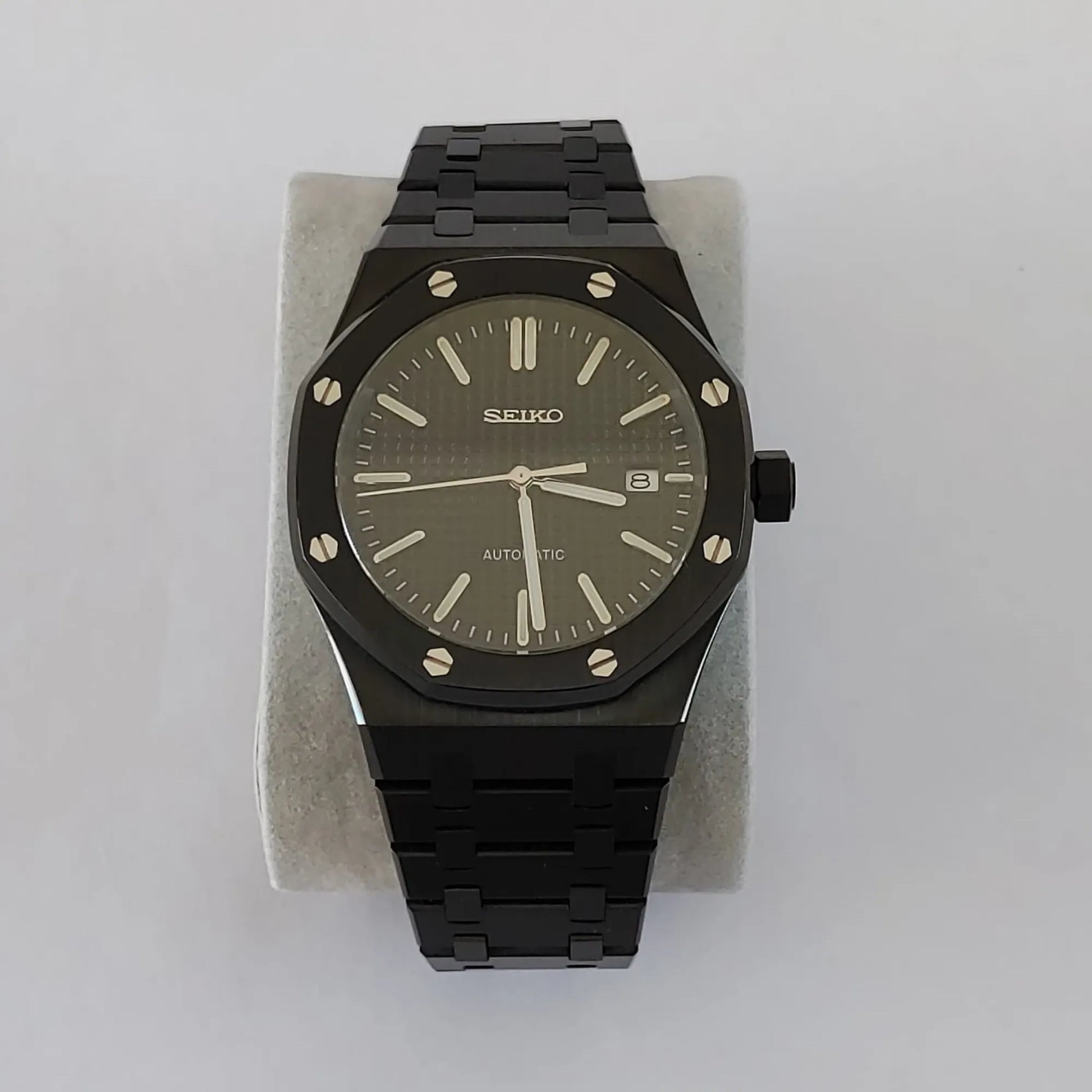 Black stainless steel Seiko watch with octagonal bezel, silver hour markers, and date display at 3 o'clock.