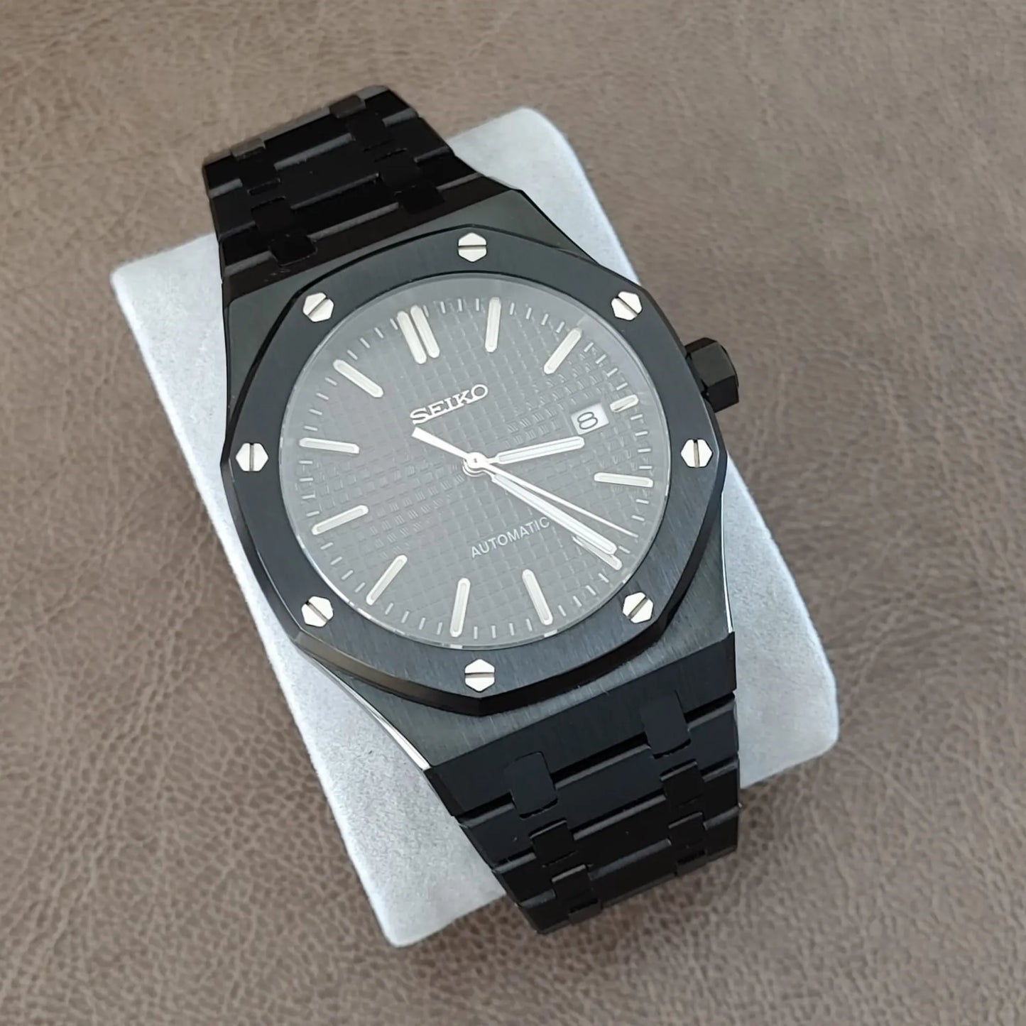 Black and silver Seiko NH35 watch with octagonal bezel, textured dial, and metal link bracelet.