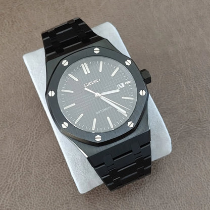 Black and silver Seiko NH35 watch with octagonal bezel, textured dial, and metal link bracelet.