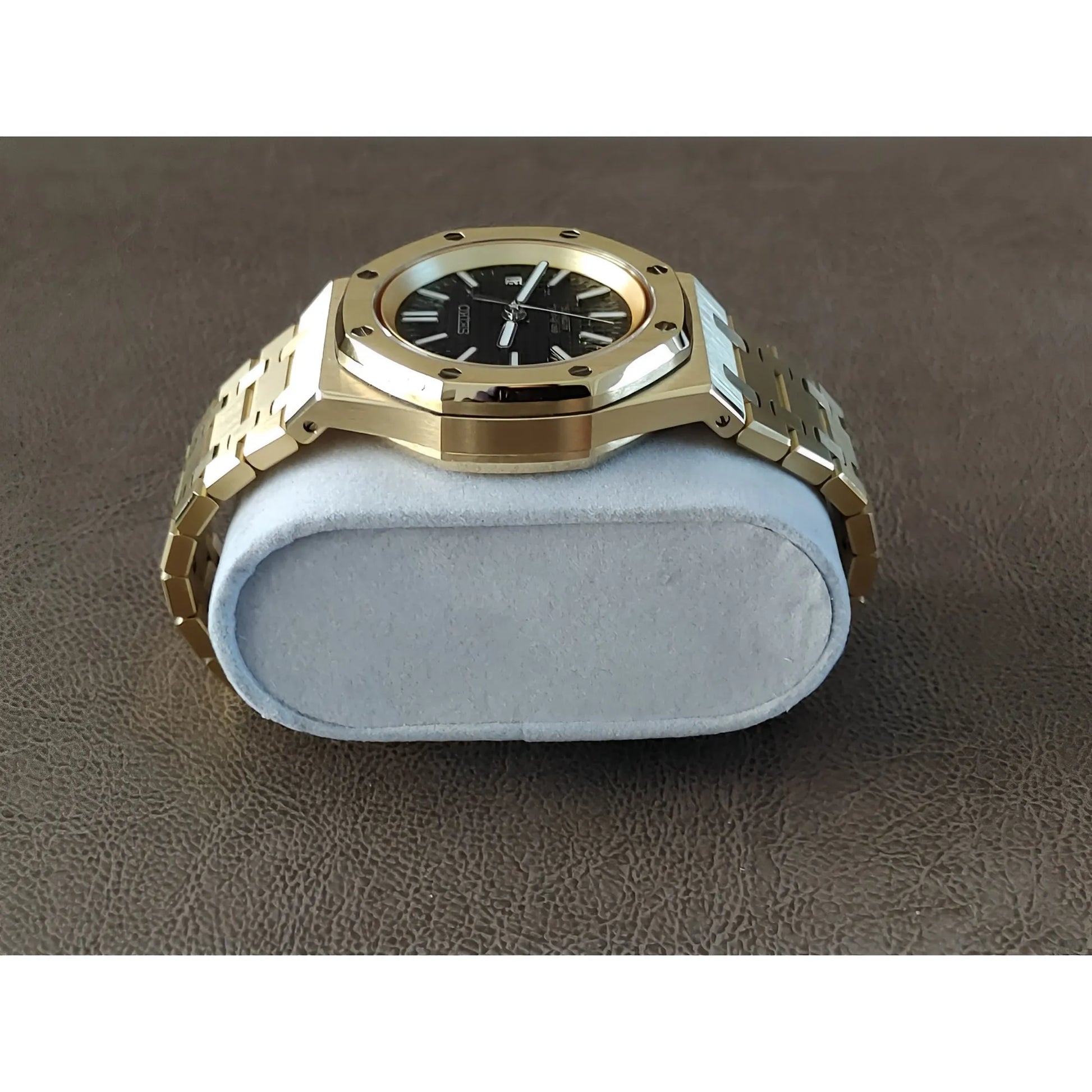 Gold-tone stainless steel Seiko watch with black dial, octagonal bezel, and bracelet band on cushion display.