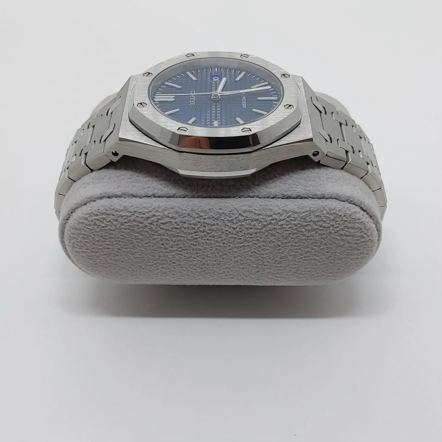 Seiko NH35 watch with navy blue octagonal dial, silver stainless steel case, and linked bracelet on a gray cushion.