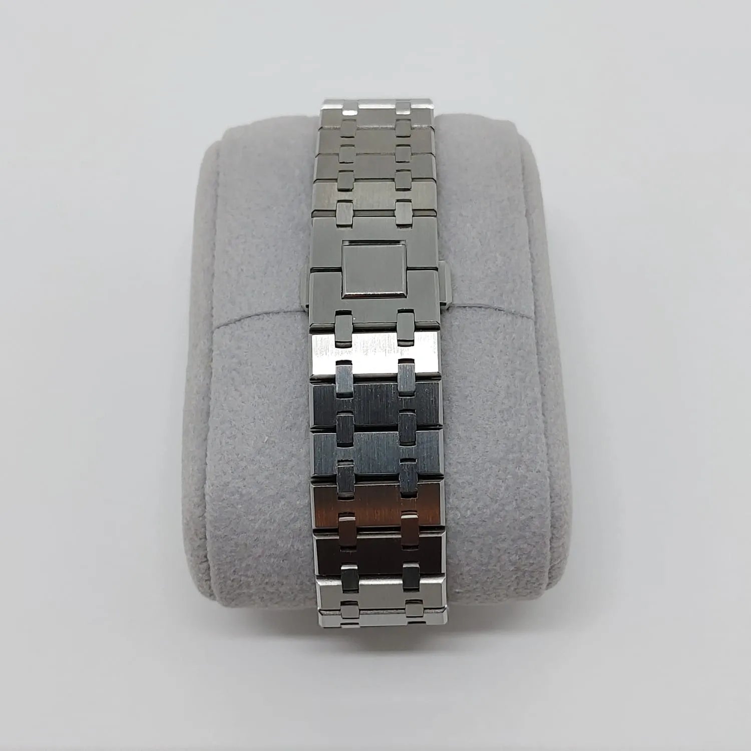 Stainless steel watch bracelet with polished and brushed links on a gray cushion display.