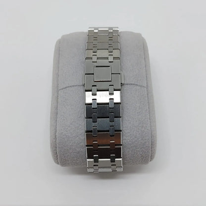Stainless steel watch bracelet with polished and brushed links on a gray cushion display.