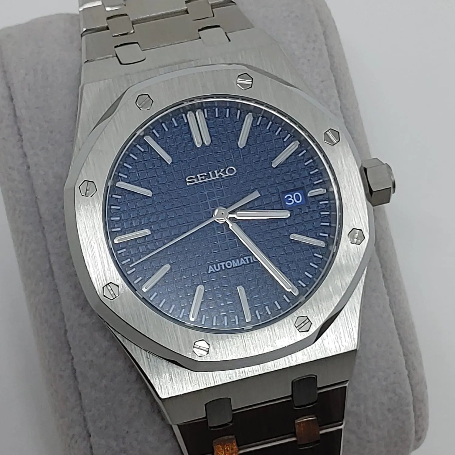 Seiko NH35 watch with textured navy blue dial, silver hour markers, date window, and stainless steel bracelet.