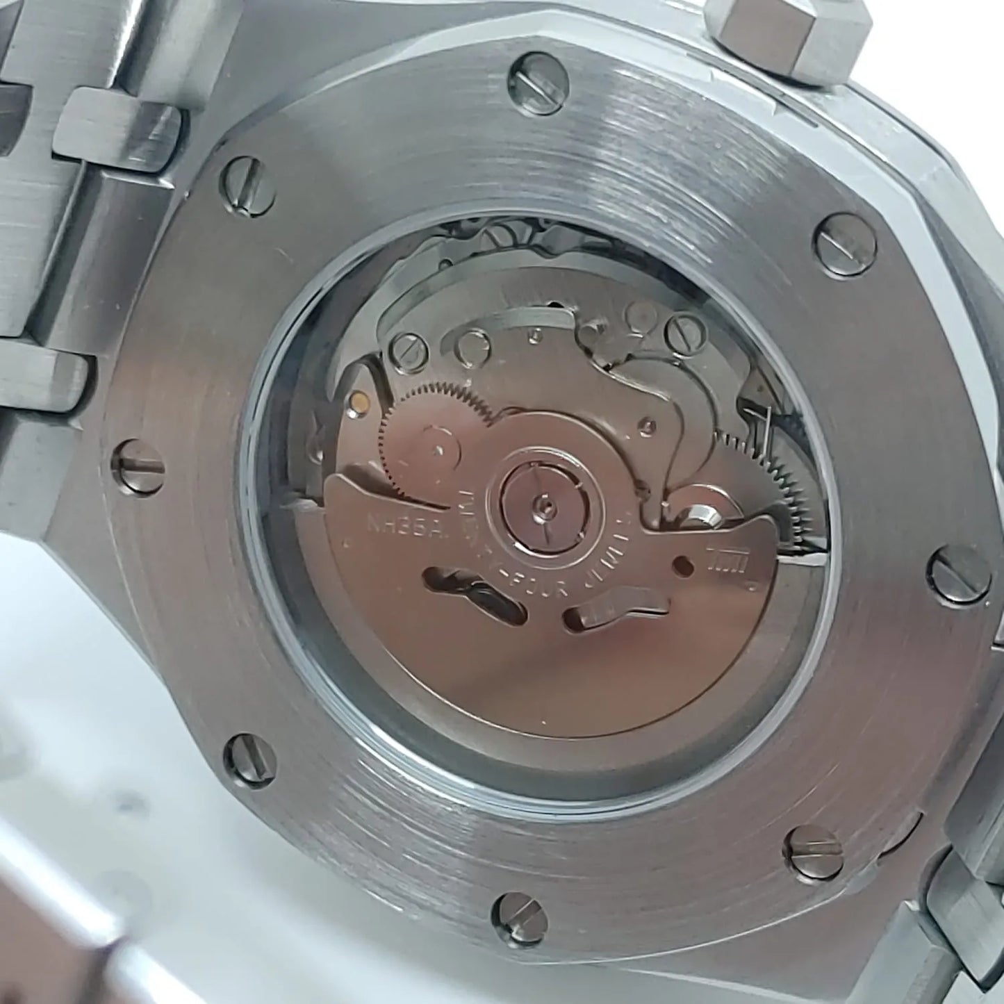Close-up of a stainless steel watch back with visible Seiko NH35 automatic movement through a clear case window.