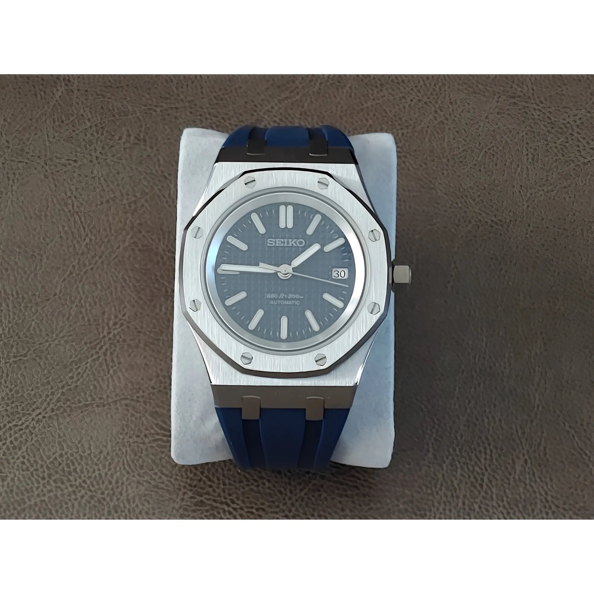 Royal Oak style watch with navy blue textured dial, silver markers, and blue rubber strap.