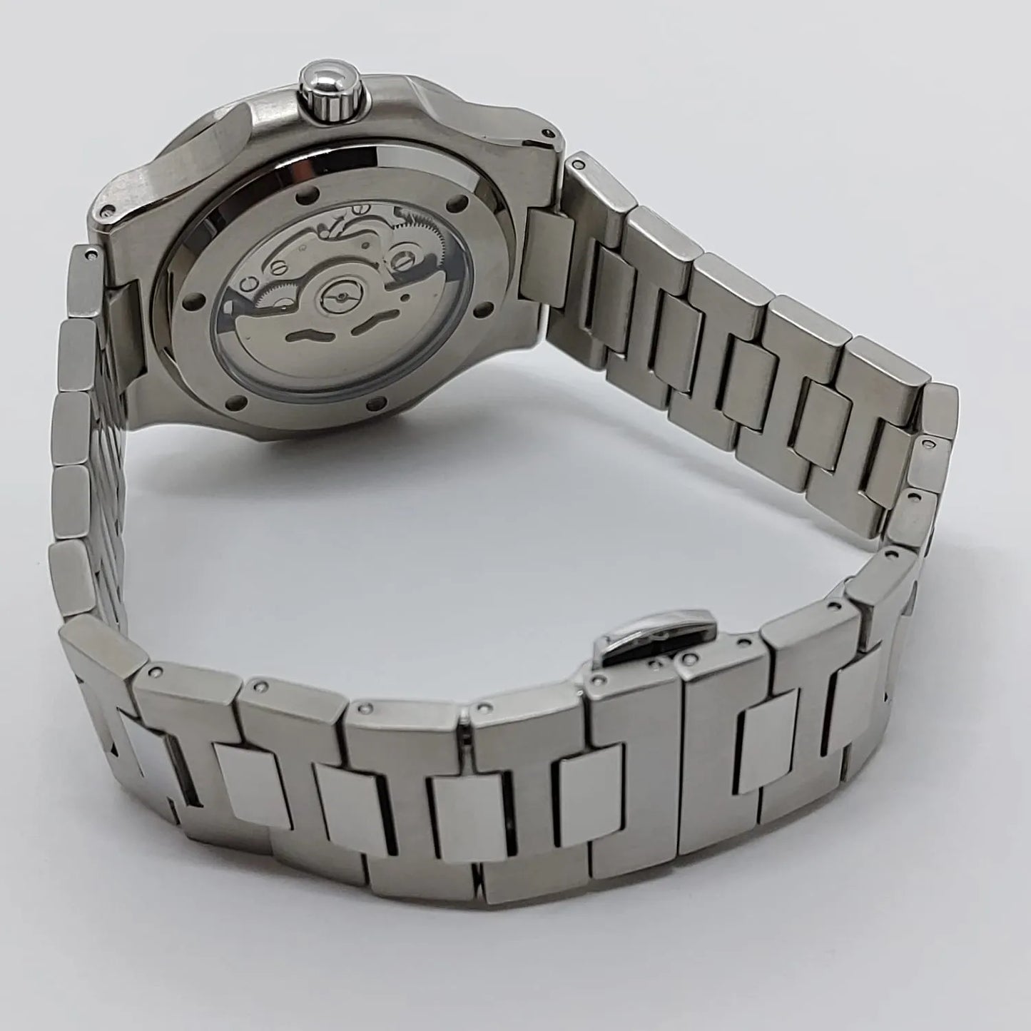 Stainless steel wristwatch with polished bracelet and transparent case back showing mechanical movement.