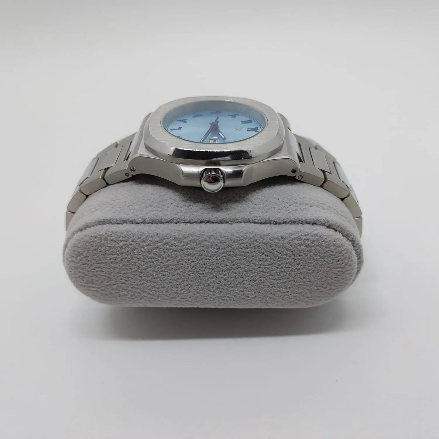 Silver stainless steel watch with round 40mm ice blue dial and Arabic numerals on gray cushion stand.