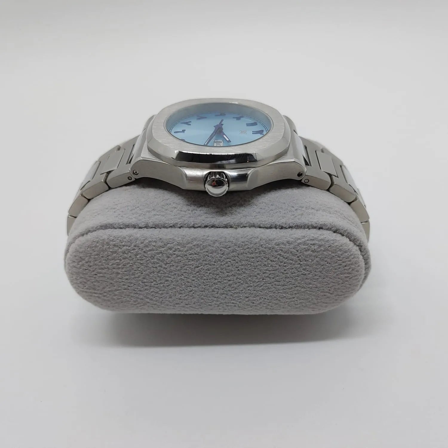 Silver stainless steel watch with round 40mm ice blue dial and Arabic numerals on gray cushion stand.
