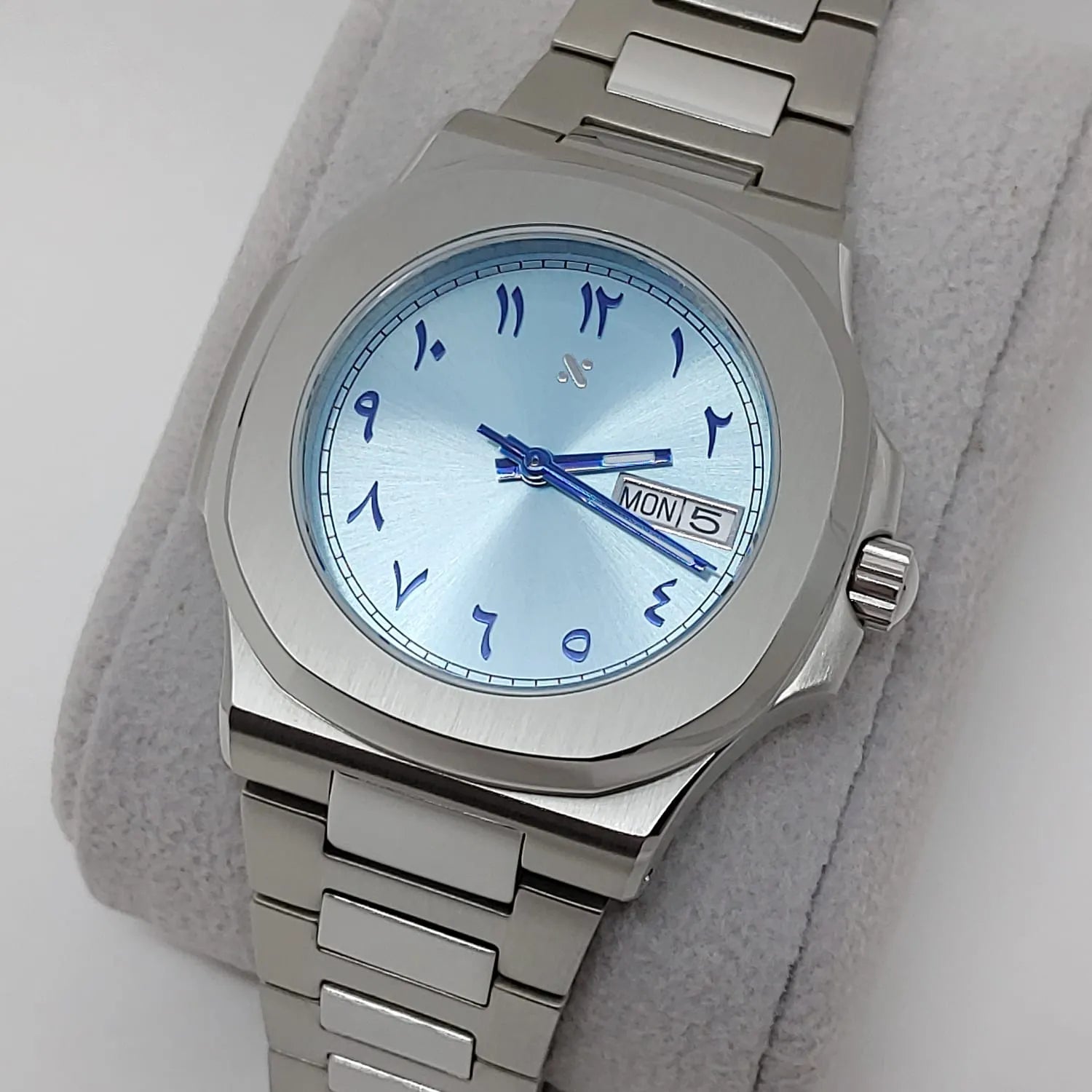 Stainless steel watch with 40mm ice blue dial, blue Arabic numerals, day-date display, and matching blue hands.