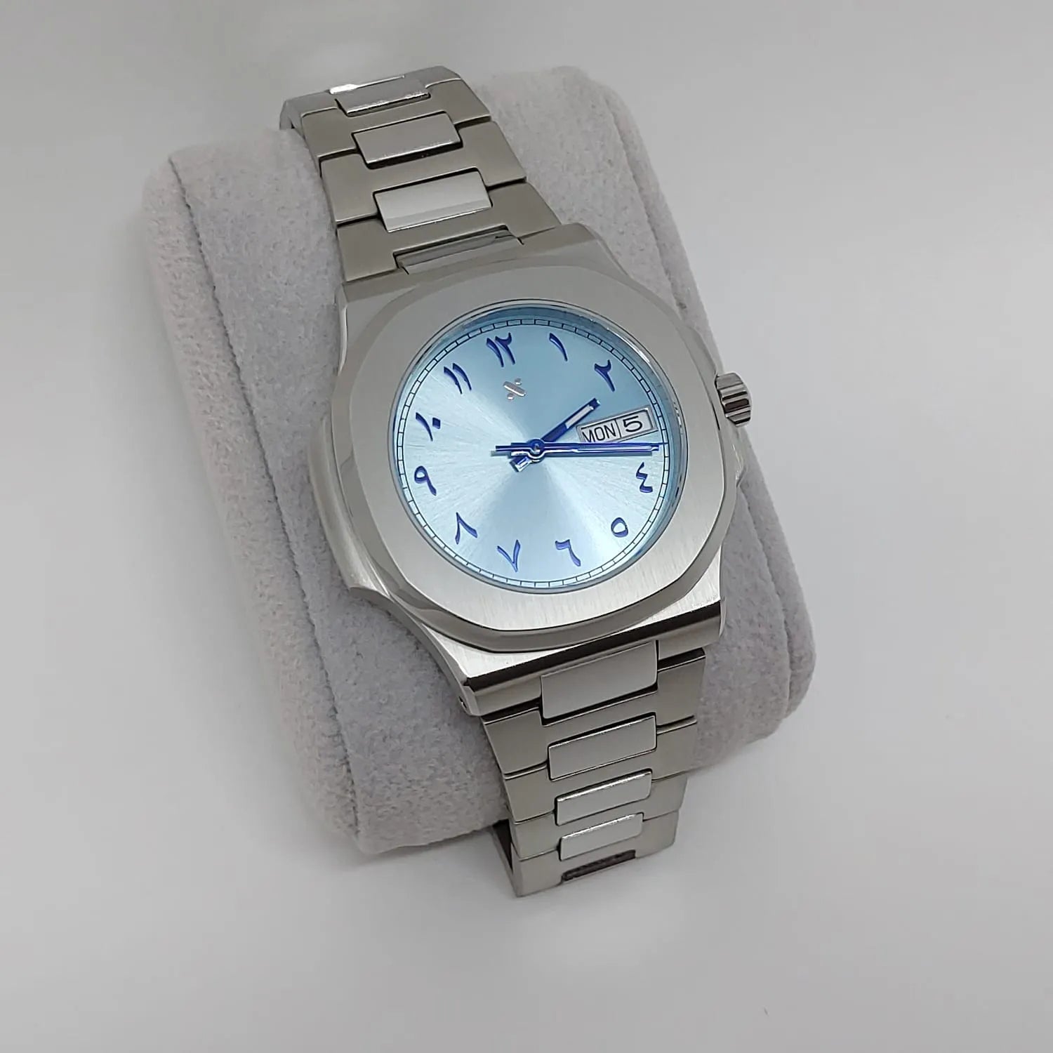 Stainless steel Nautilus-style watch with 40mm ice blue dial and blue Arabic numerals, silver hands, day-date window at 3.