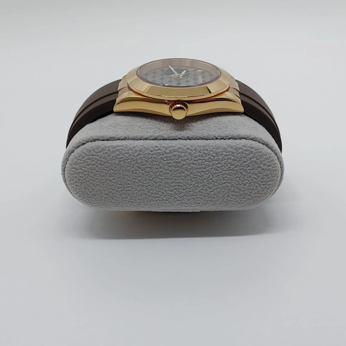 Gold-tone Seiko NH38 watch with guilloche patterned gray dial and brown leather strap on gray cushion.