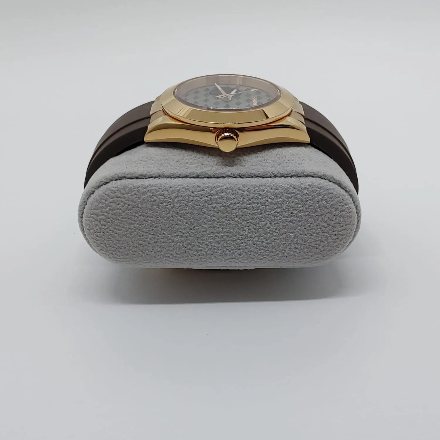 Gold-tone Seiko NH38 watch with guilloche patterned gray dial and brown leather strap on gray cushion.