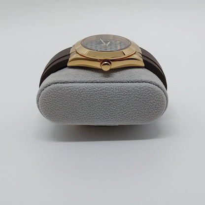 Gold-tone Seiko NH38 watch with guilloche patterned gray dial and brown leather strap on gray cushion.
