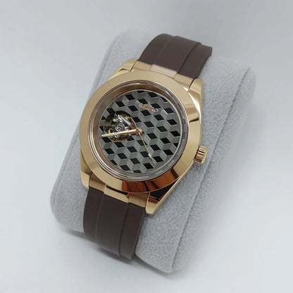Gold-tone round watch with a grey hemicube guilloche dial and brown rubber strap.