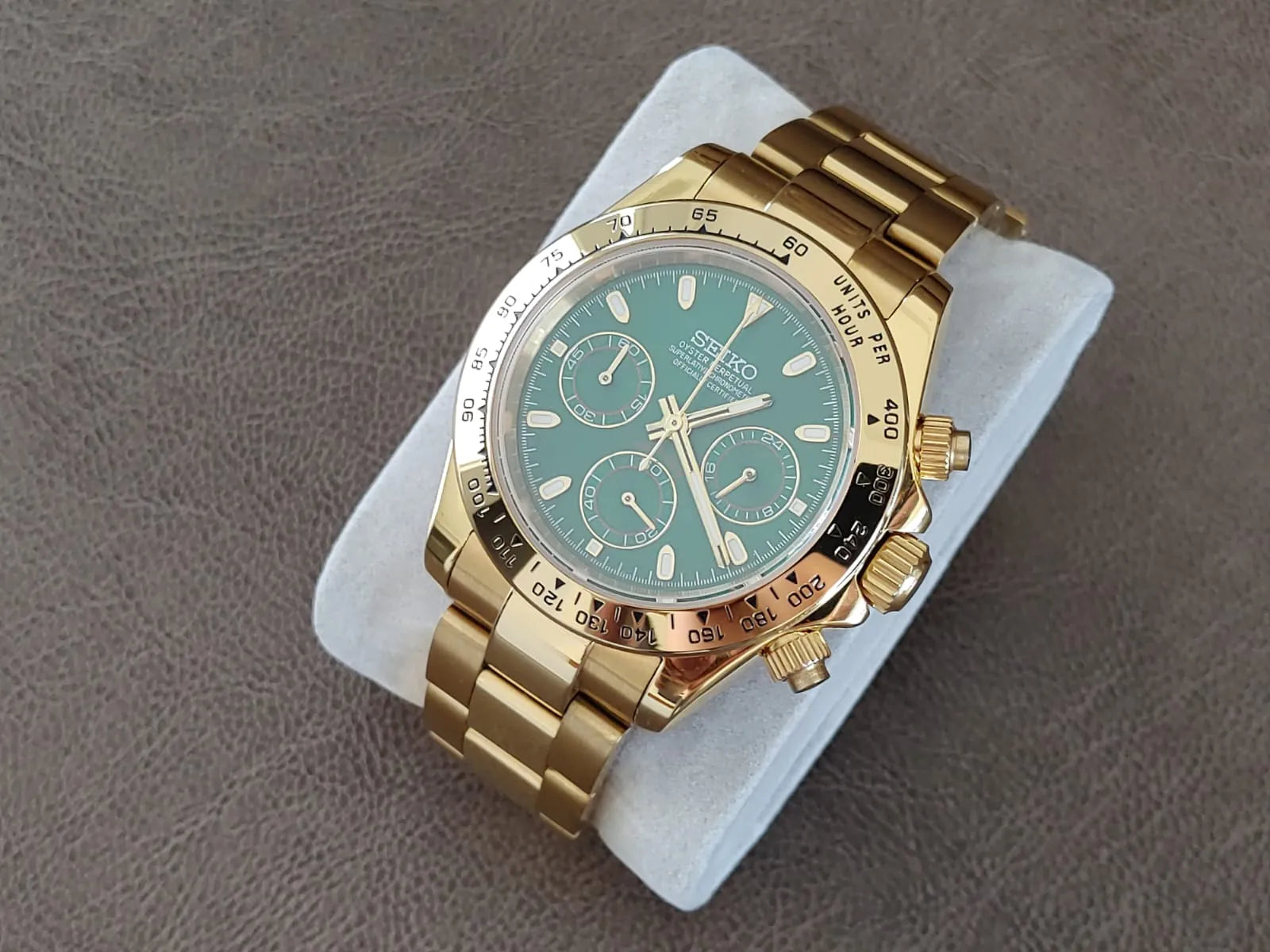 Gold stainless steel Seiko chronograph watch with green dial and three subdials on metal link bracelet.
