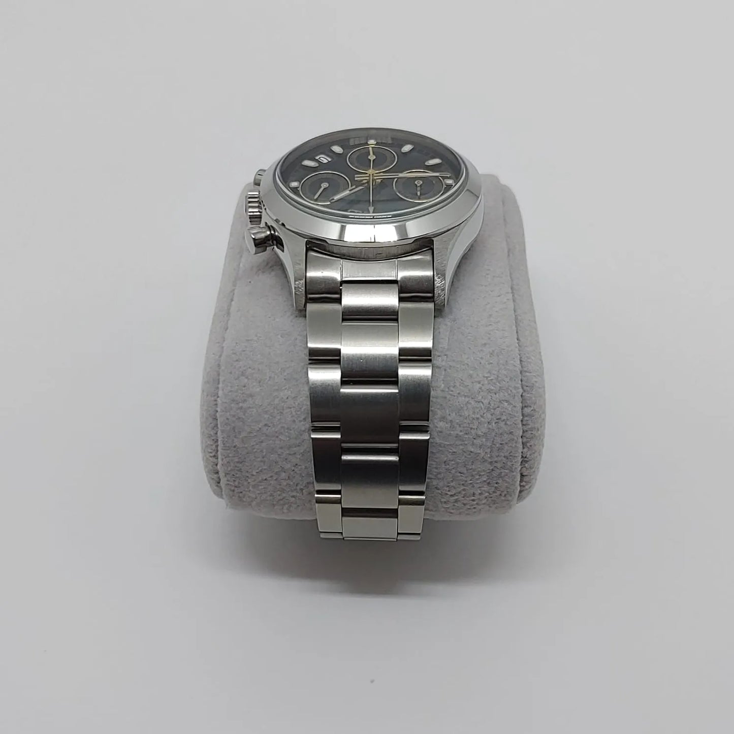 Seiko VK63 vintage watch with black dial, silver hour markers, and stainless steel bracelet on gray cushion.