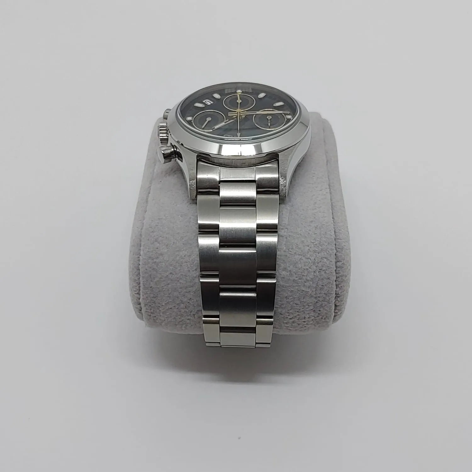 Seiko VK63 vintage watch with black dial, silver hour markers, and stainless steel bracelet on gray cushion.