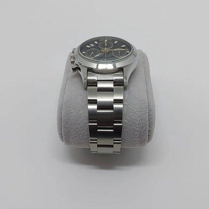 Seiko VK63 vintage watch with black dial, silver hour markers, and stainless steel bracelet on gray cushion.