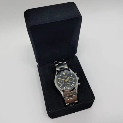 Seiko VK63 chronograph watch with black dial, gold-tone markers, and stainless steel bracelet in black velvet box.