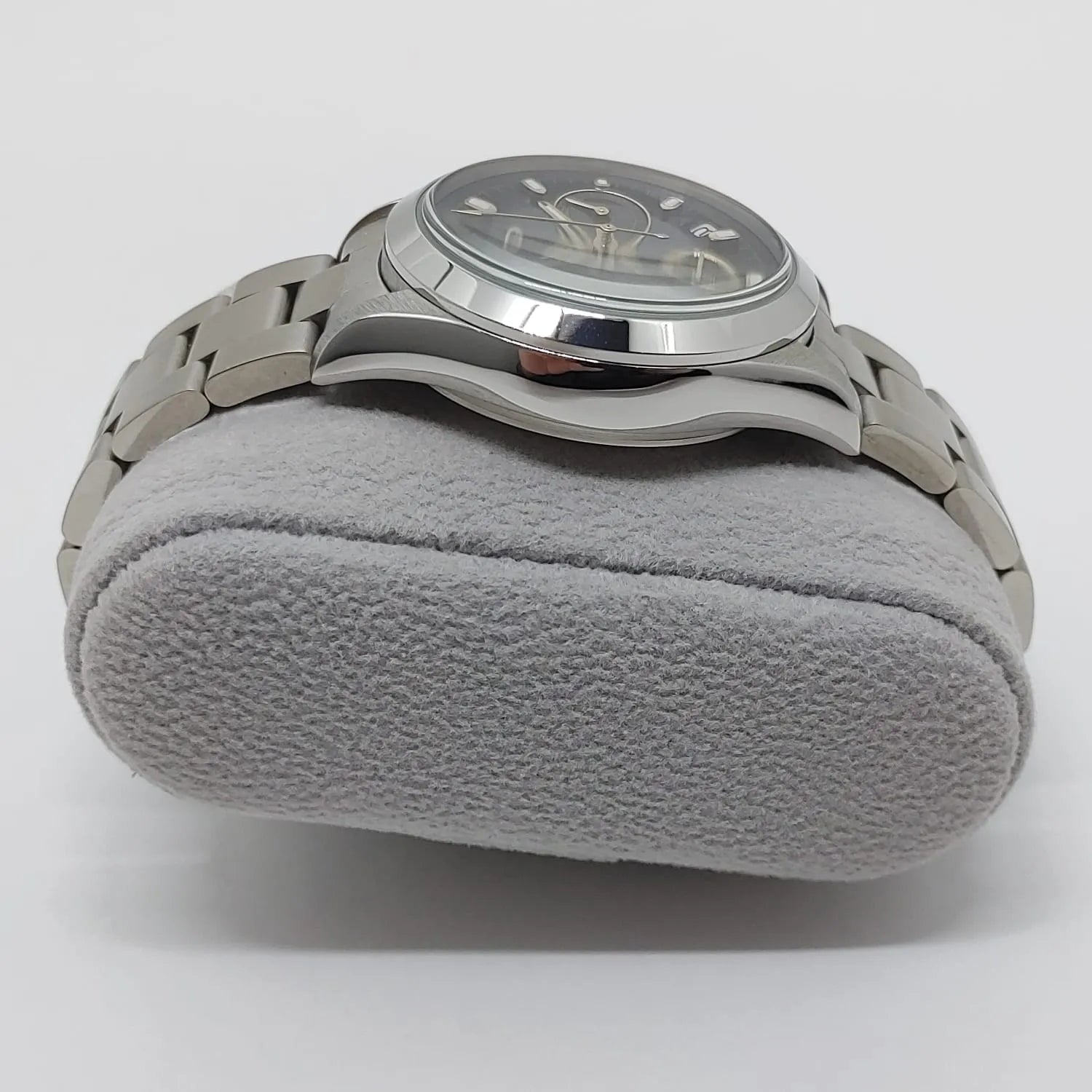 Seiko stainless steel wristwatch with black dial, silver markers, and metal link bracelet on gray cushion.