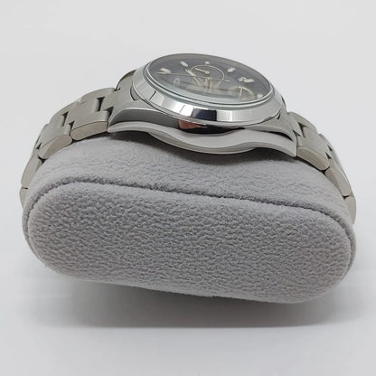 Seiko stainless steel wristwatch with black dial, silver markers, and metal link bracelet on gray cushion.