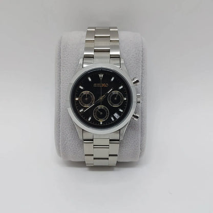 Stainless steel Seiko wristwatch with black dial, gold-tone subdials, and silver bracelet band.