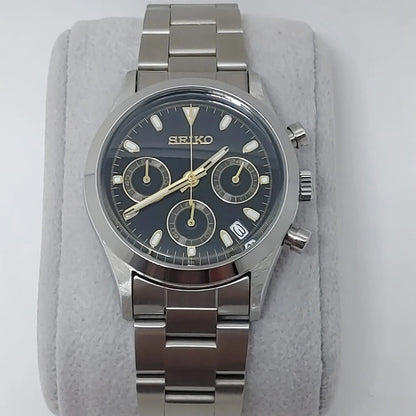 Seiko VK63 chronograph watch with black dial, gold-tone hands and markers, stainless steel case and bracelet, and date.
