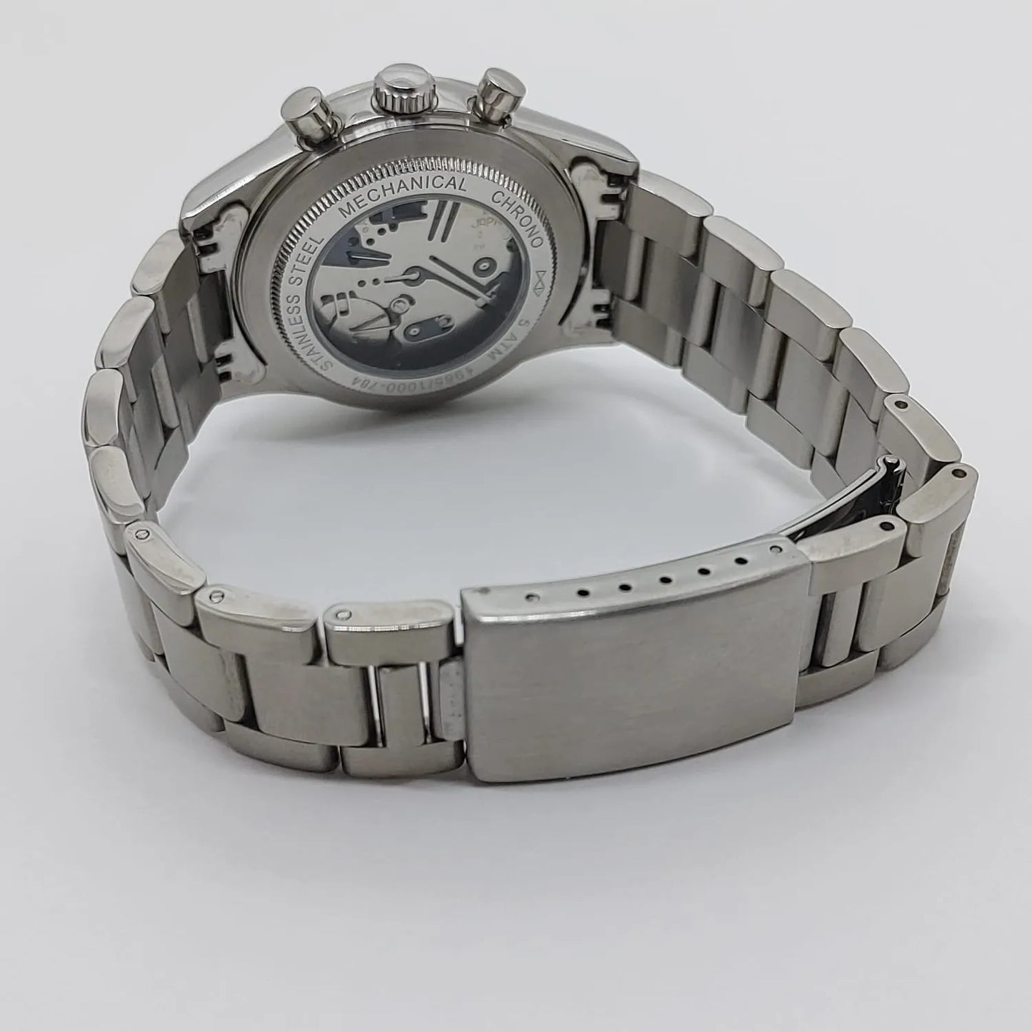Seiko VK63 watch with stainless steel bracelet and open case back showing mechanical movement.