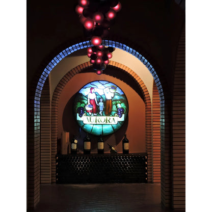 Wine cellar archway with brick walls, illuminated stained glass sign reading Aurora, and wine bottles on a counter beneath.