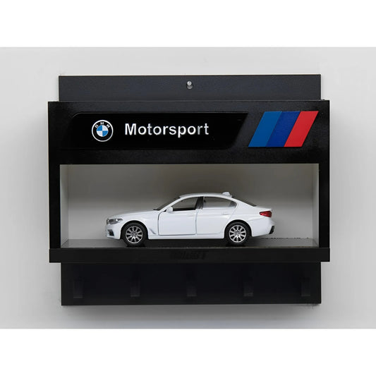 Black wall key hook rack with BMW Motorsport logo and red-blue stripes, featuring a white scale model car display.
