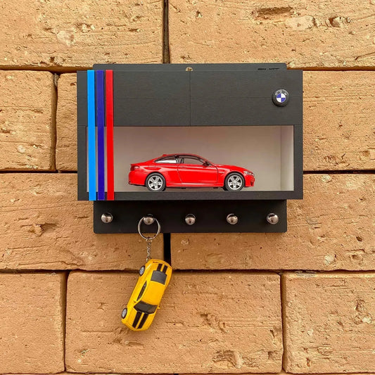 Black rectangular wall key hook rack with BMW logo, red scale model car inside, and yellow car key hanging.