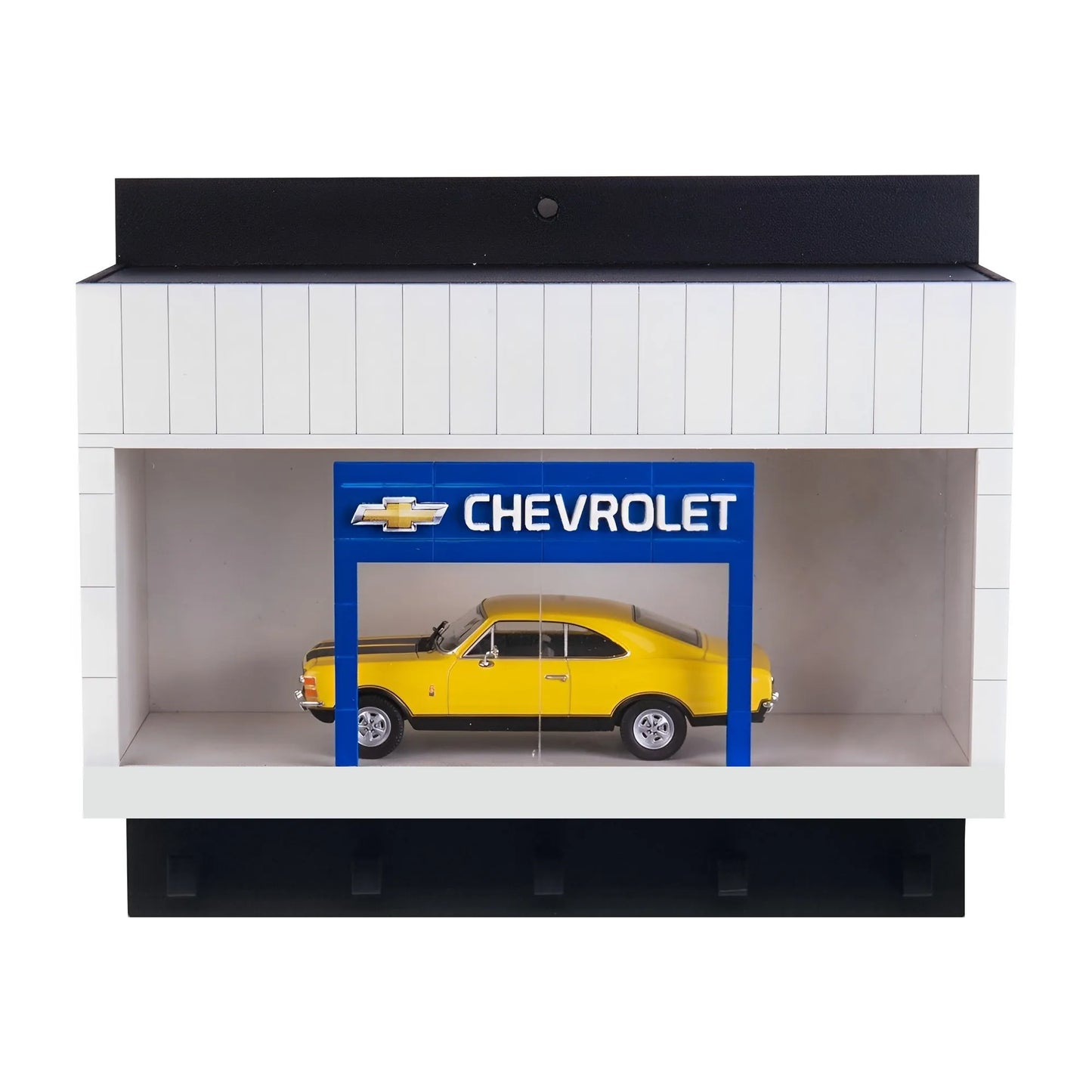 White wall key hook rack with black hooks and a scale model yellow Chevrolet car displayed inside under a blue Chevrolet sign.