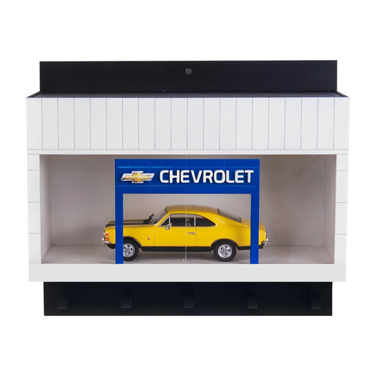 White wall key hook rack with black hooks and a scale model yellow Chevrolet car displayed inside under a blue Chevrolet sign.