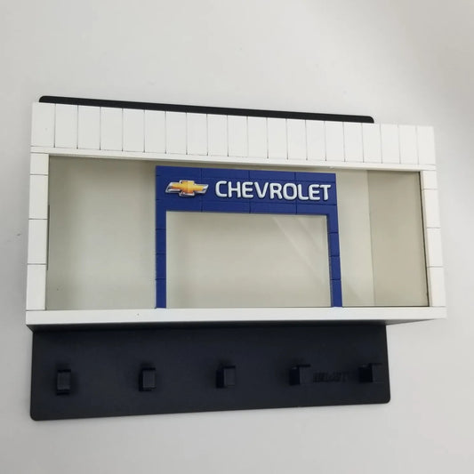 Black wall-mounted key hook rack featuring a white and blue Chevrolet scale model car display case.