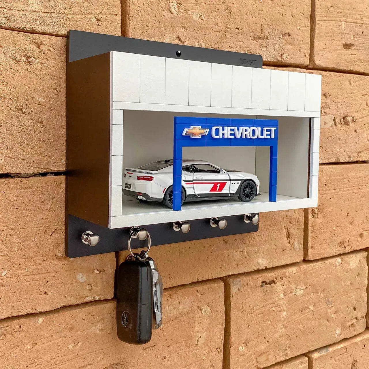 Wall-mounted Chevrolet key hook rack with scale model car display and four silver hooks.