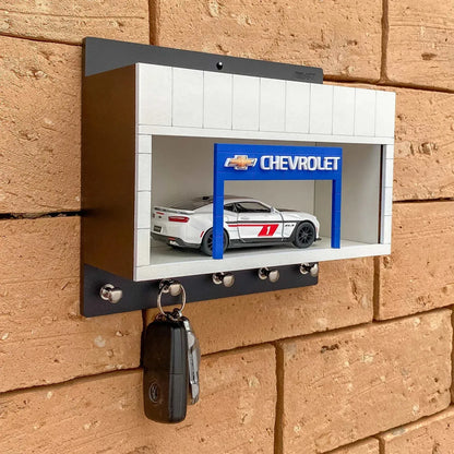 Wall-mounted Chevrolet key hook rack with scale model car display and four silver hooks.