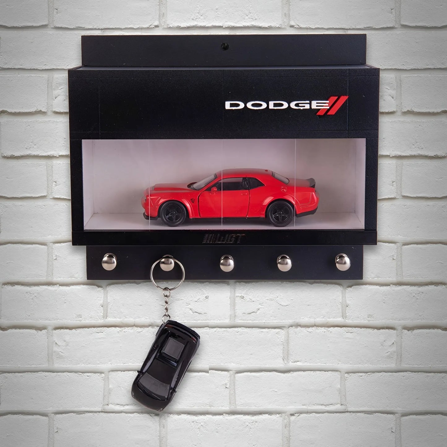 Black wall-mounted key hook rack with clear display case holding red Dodge model car and three metal hooks, one with a.