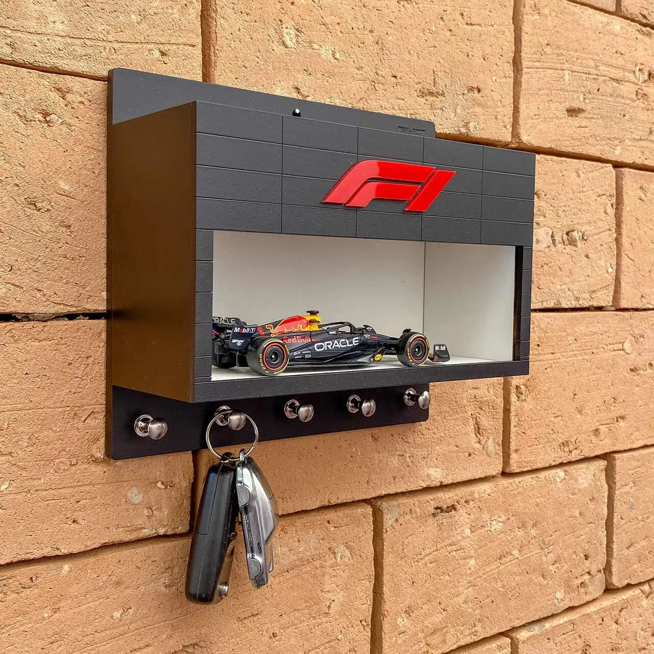 Black wall-mounted F1 key hook rack with red F1 logo and scale model race car display shelf.