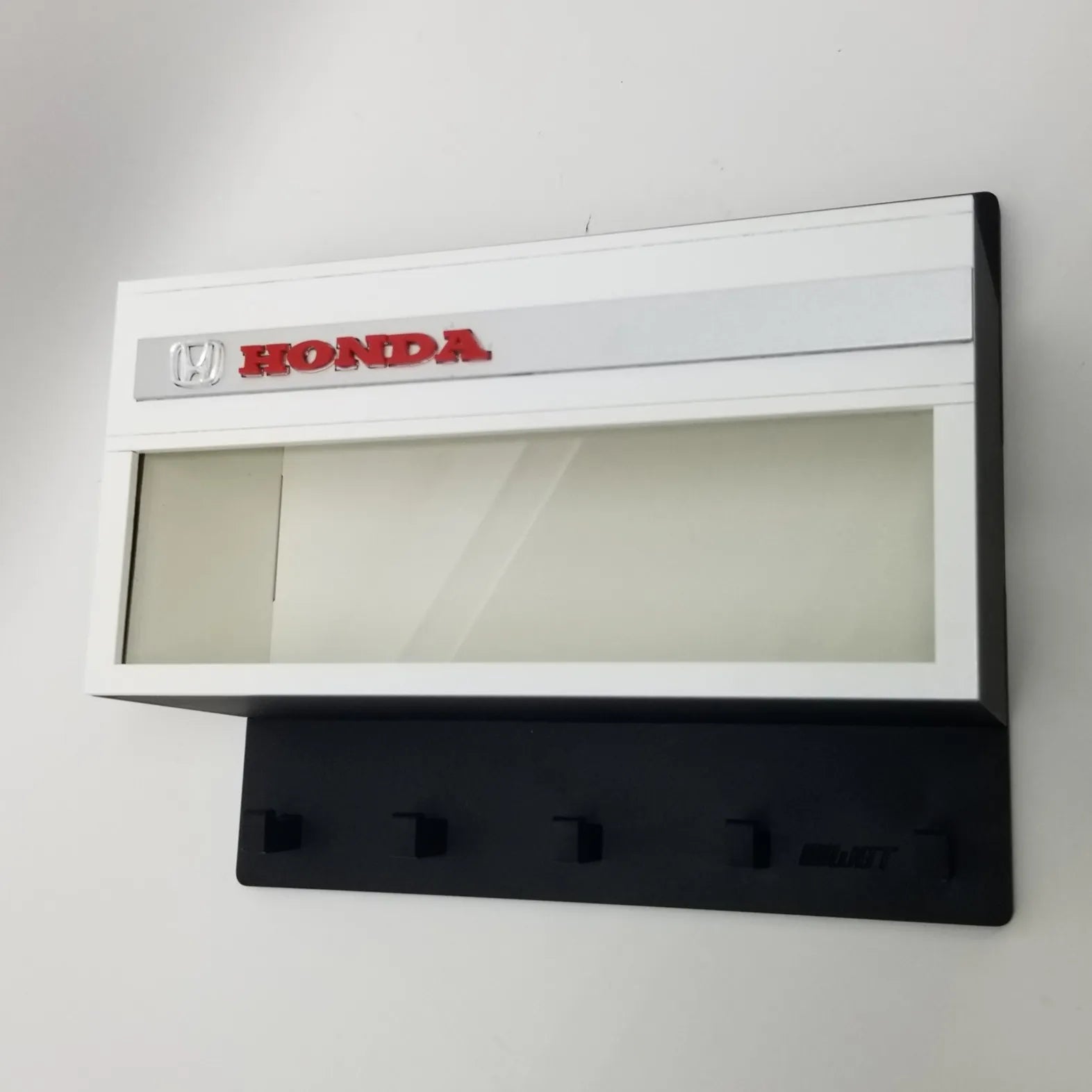 Honda wall-mounted key hook rack with white display case and red Honda logo.