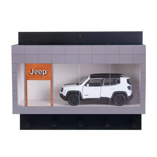 Miniature white Jeep SUV displayed inside a gray wall-mounted key hook rack shaped like a showroom with a Jeep logo.