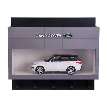Gray and black Land Rover wall key hook rack shaped like a showroom with a white SUV scale model inside.
