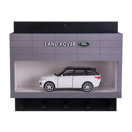 Gray and black Land Rover wall key hook rack shaped like a showroom with a white SUV scale model inside.