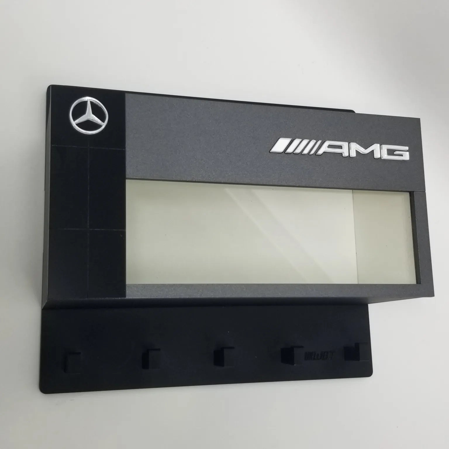 Black Mercedes AMG wall-mounted key hook rack with five hooks and logo panel above.