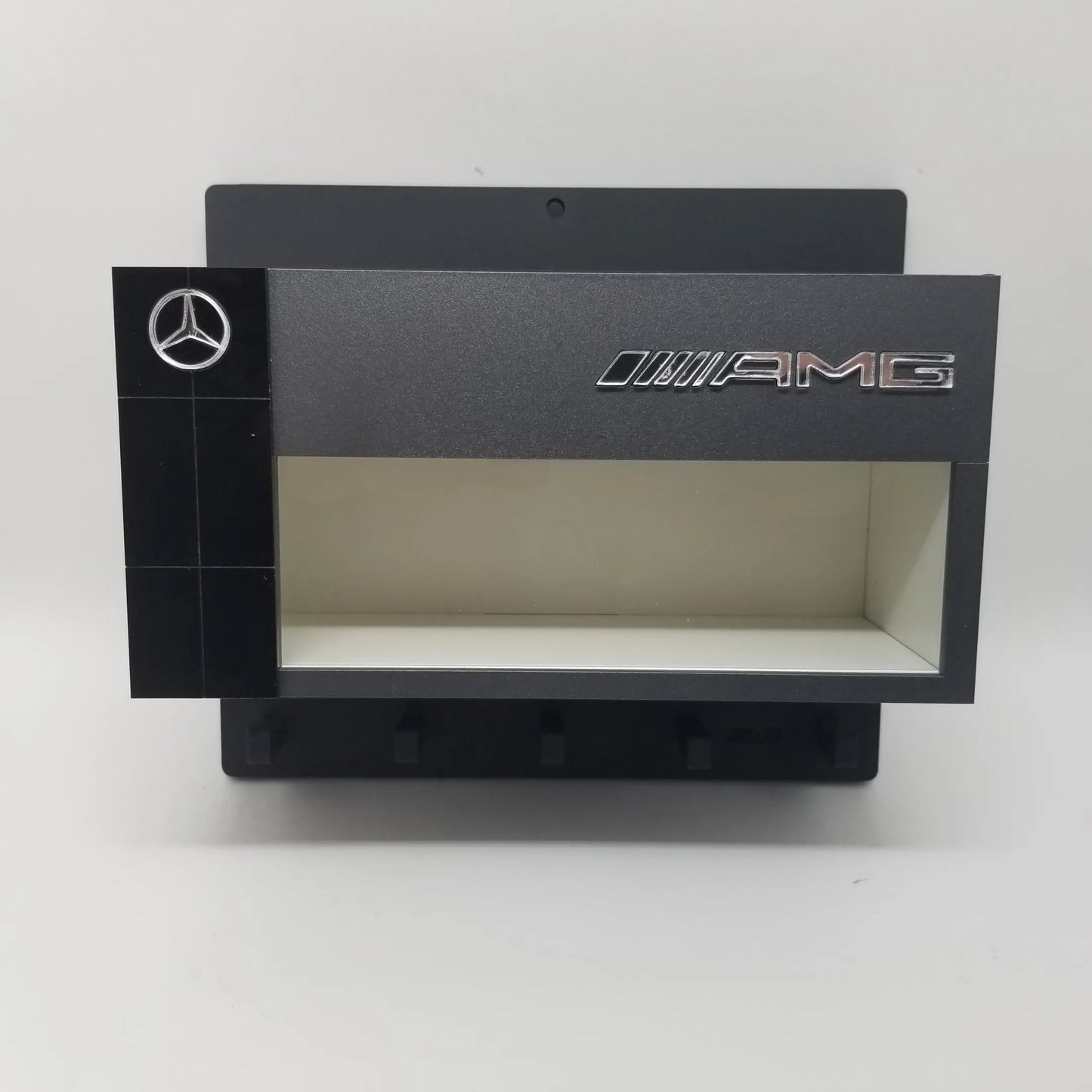 Black Mercedes AMG wall key hook rack with scale model car display case and five hooks.