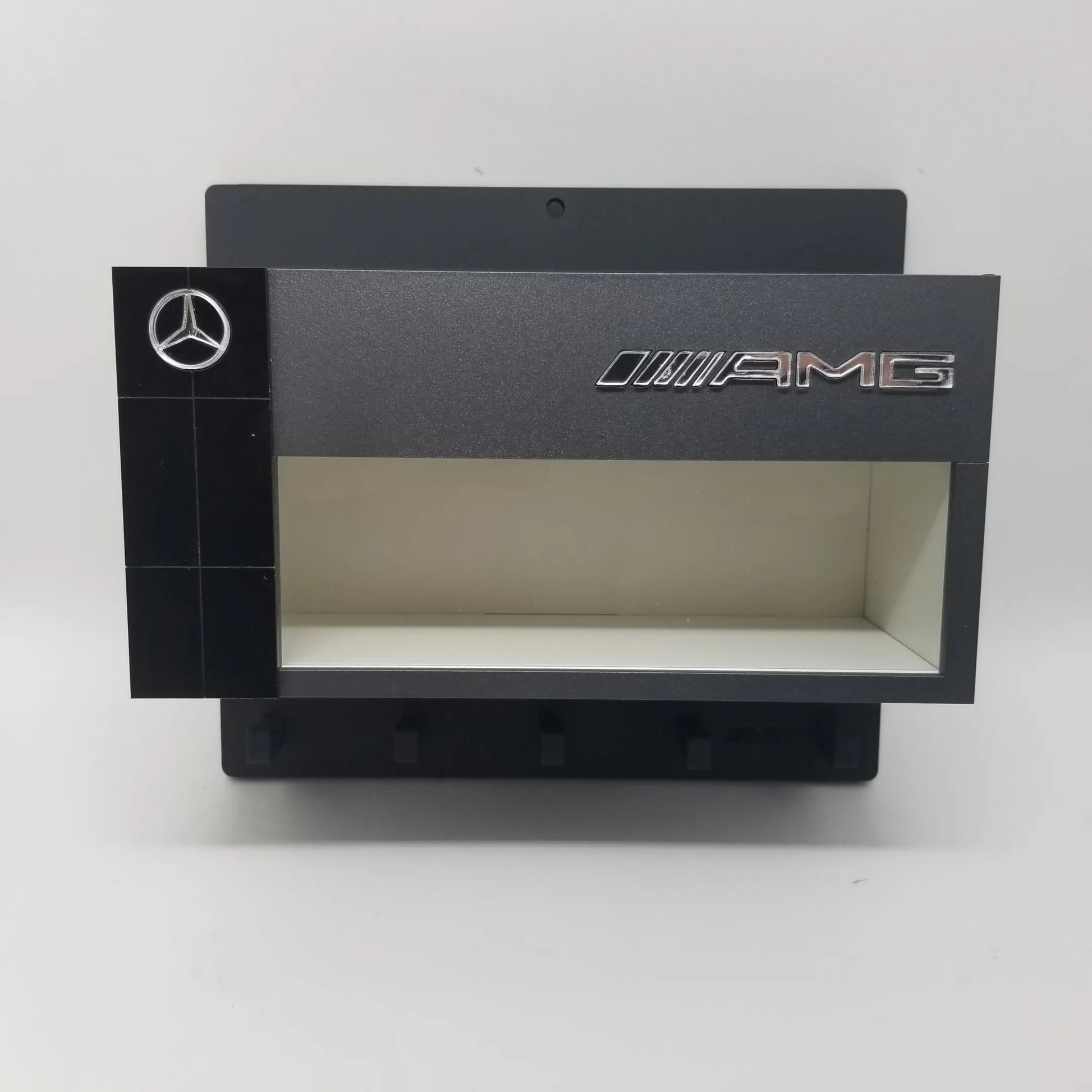 Black Mercedes AMG wall key hook rack with scale model car display case and five hooks.