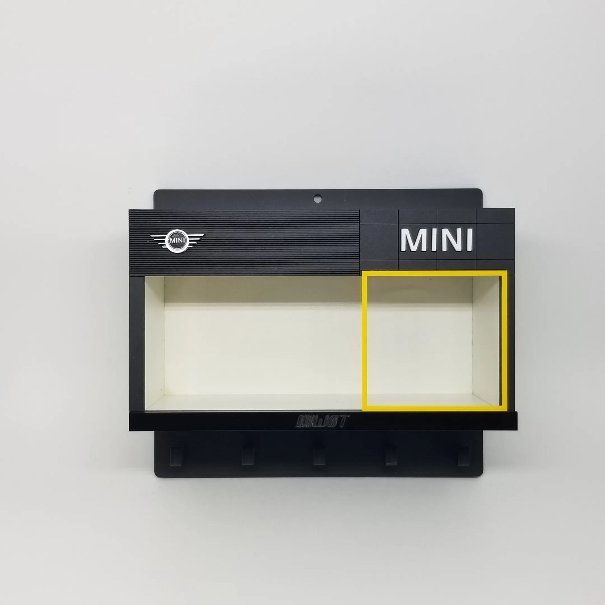 Black wall-mounted key hook rack with MINI logo and display case for scale model cars.