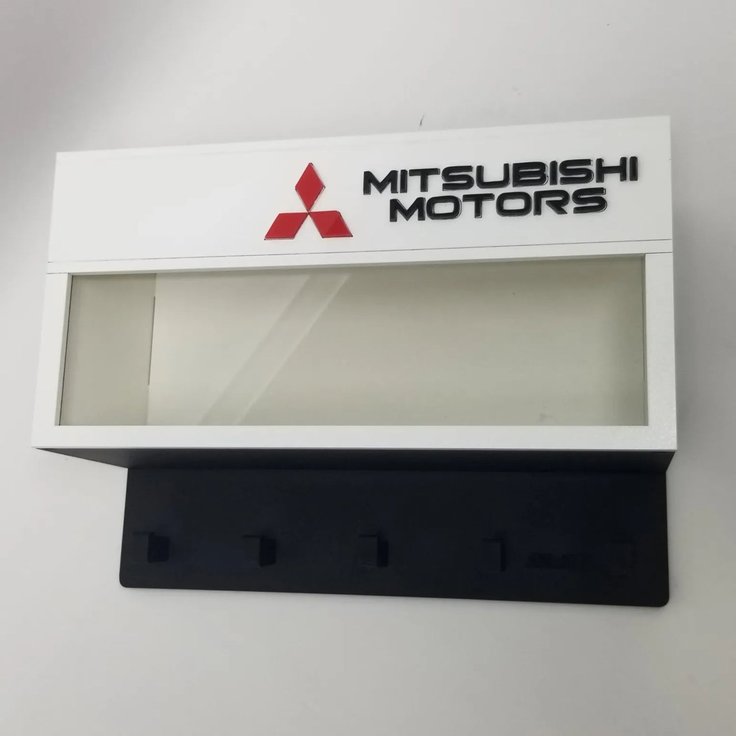 White Mitsubishi Motors wall key hook rack with red logo and four black hooks.